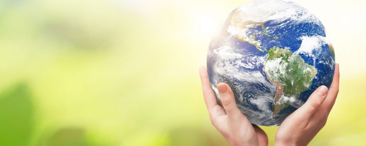 Hands holding the Earth in front of a green background