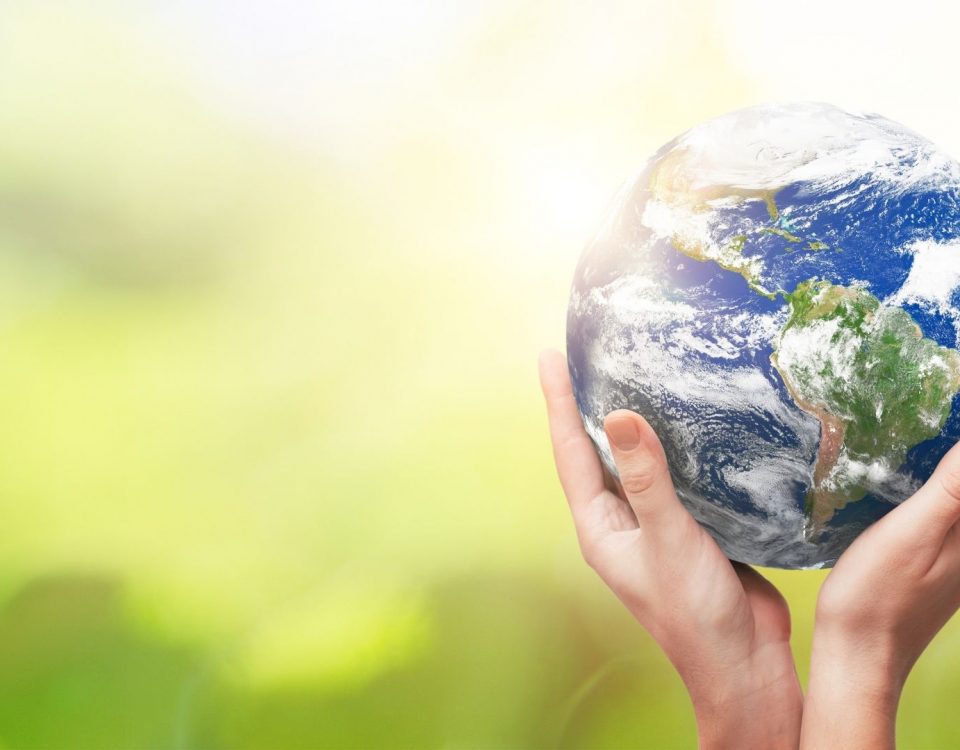 Hands holding the Earth in front of a green background
