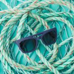 Sunglasses made from used ocean plastic resting on rope